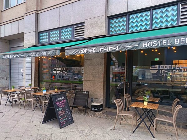 Exterior of Coffee INN Hostel with café tables on the pavement
